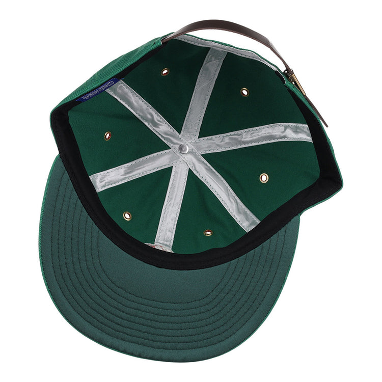 The Ebbets Field Hot Spring Bathers MiLB Cotton Ballcap features a green design with white X-pattern seam tape, metal eyelets, a black sweatband, and an adjustable brown leather strap viewed from the inside.