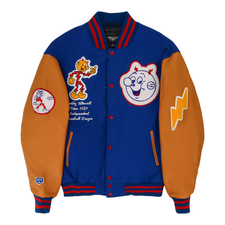 The Ebbets Field Reddy Kilowatt DNA Varsity Jacket is blue and orange, with cartoon baseball patches, smiling baseball faces, a lightning bolt, and an “Officially Licensed Cooperstown Baseball League” patch.