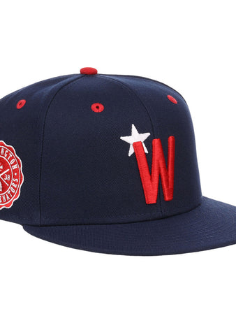 The Ebbets Field Washington Black Senators NLB Varsity Fitted Ballcap features a navy design, red and white W logo with star on the front, a side Nationals patch, flat brim, and red eyelets.