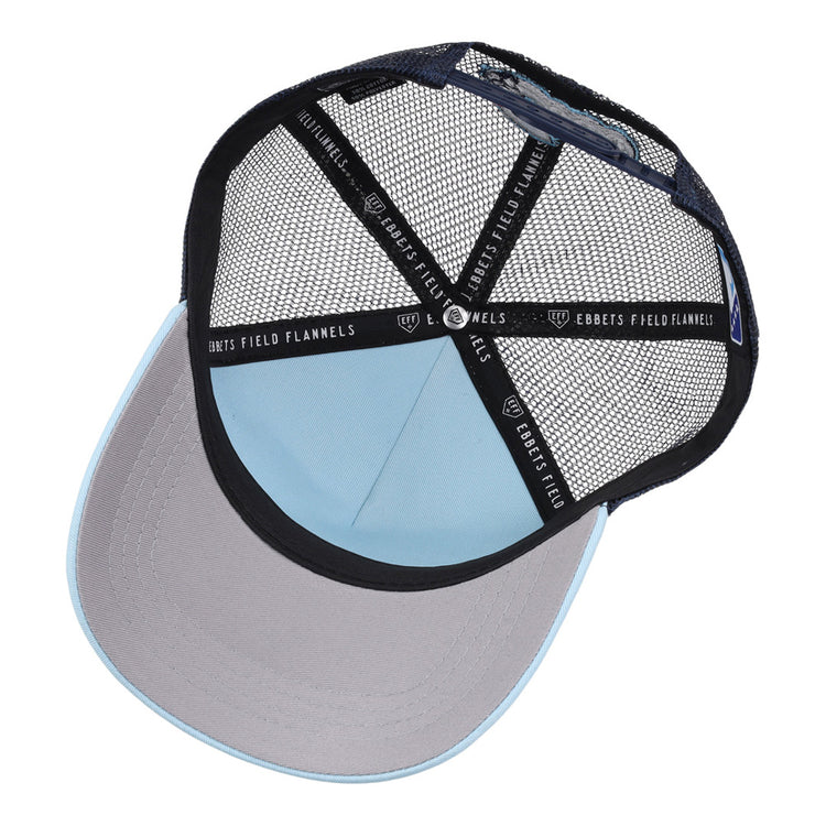 A top-down view of the Columbus Clippers MiLB Trucker Ballcap by Ebbets Field shows a light blue crown, gray brim, black mesh back, and 