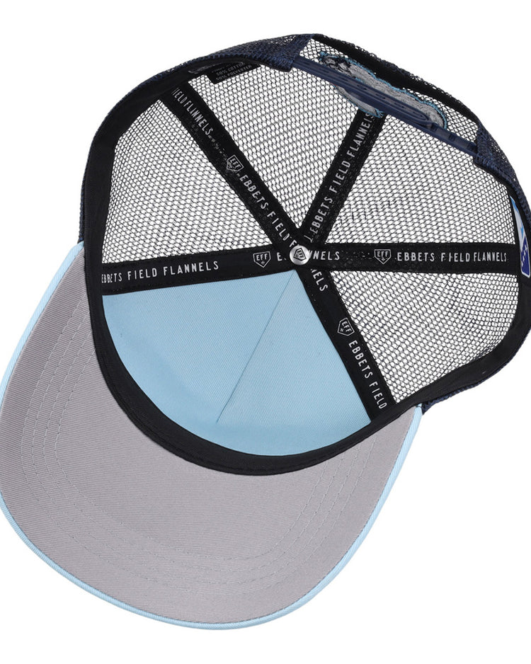 A top-down view of the Columbus Clippers MiLB Trucker Ballcap by Ebbets Field shows a light blue crown, gray brim, black mesh back, and 