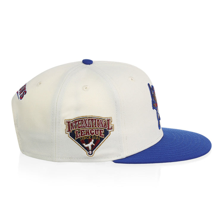 The Ebbets Field Buffalo Bisons MiLB Snapback Ballcap is a white cap with a blue brim, blue top button, and an International League embroidered patch on the side.