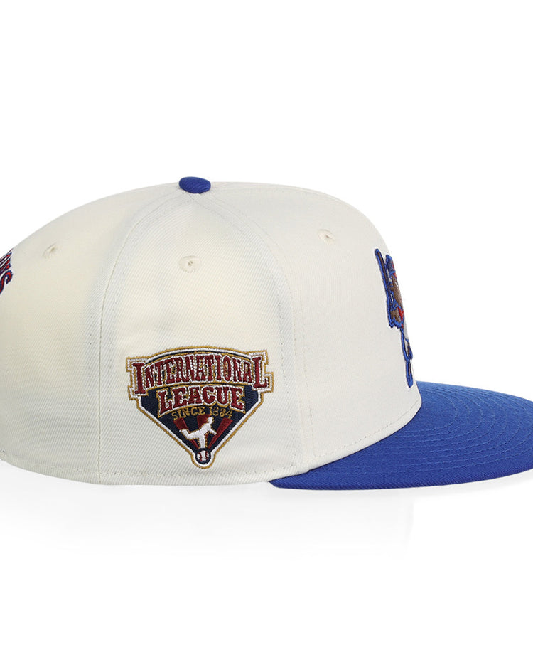 The Ebbets Field Buffalo Bisons MiLB Snapback Ballcap is a white cap with a blue brim, blue top button, and an International League embroidered patch on the side.