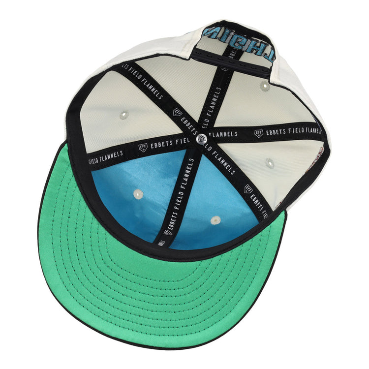 The underside of the Charlotte Knights MiLB Snapback Ballcap by Ebbets Field features a green brim, blue crown lining, black taping with “EBBETS FIELD FLANNELS” in white text, plus white eyelets and stitching inside.