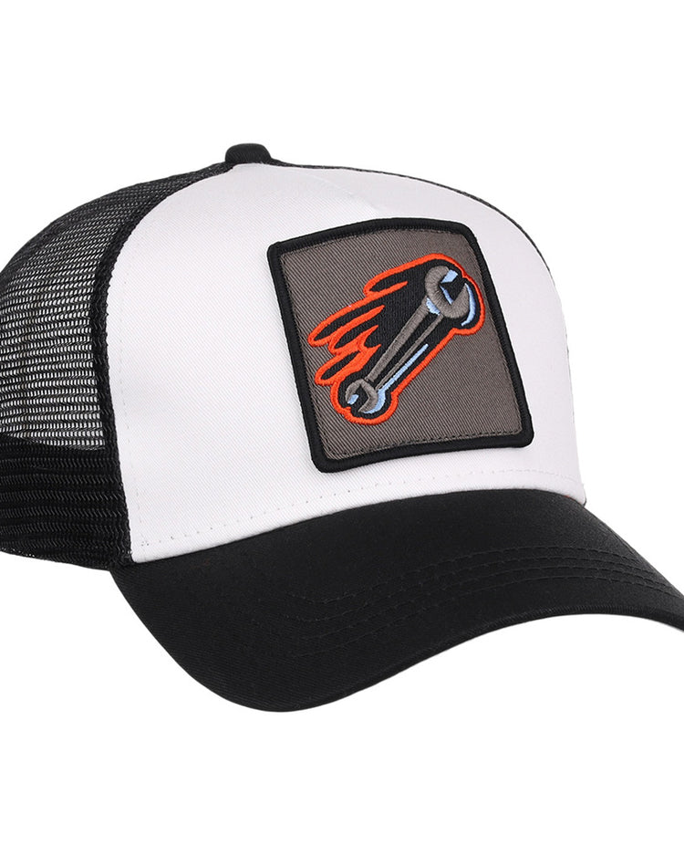 The Inland Empire 66Ers MiLB Trucker Ballcap by Ebbets Field is a black and white hat with a mesh back and a front patch showing a flaming wrench on a gray background.