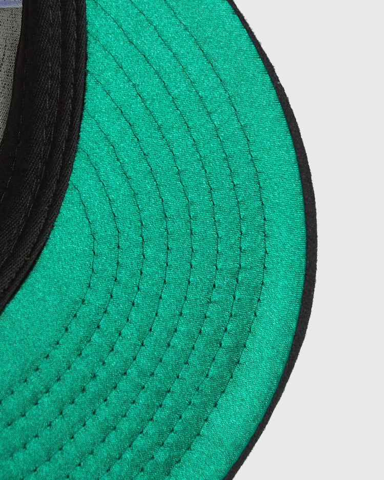 Close-up of the bright green underside of a Mission Bears Vintage Inspired Wool Ballcap brim, featuring black stitching and a black edge trim.