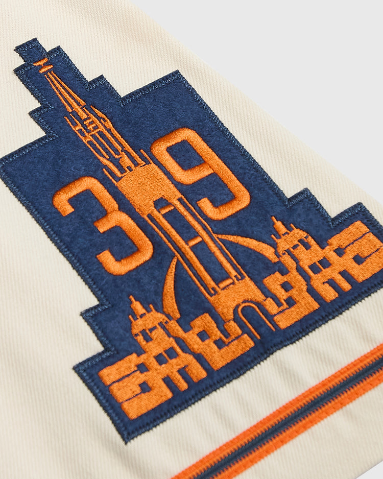 Cream-colored Ebbets Field San Francisco Seals 1938 Cotton Twill Jersey featuring an embroidered navy and orange patch of a 1946 San Francisco Sea Lions bridge, city buildings, and the numbers 39.