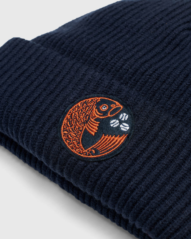 Navy blue Hiroshima Carp Felt Patch Ribbed Beanie featuring an embroidered patch of an orange fish next to three small white baseballs.