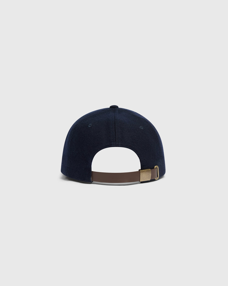 Back view of a navy wool Mystery Caps of Mexico – La Junta de Nuevo Laredo 1940 Wool Ballcap by Ebbets Field, featuring an adjustable brown leather strap and a brass buckle.