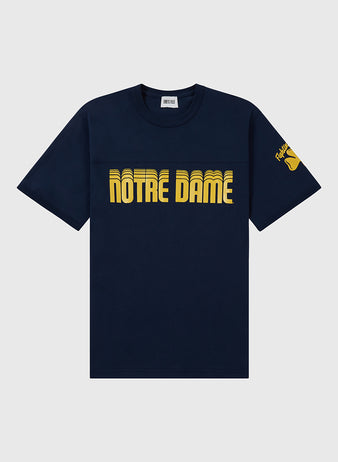 The Ebbets Field NOTRE DAME FOOTBALL TEE NAVY features bold yellow “NOTRE DAME” lettering on the chest and a yellow shamrock with text on the left sleeve.