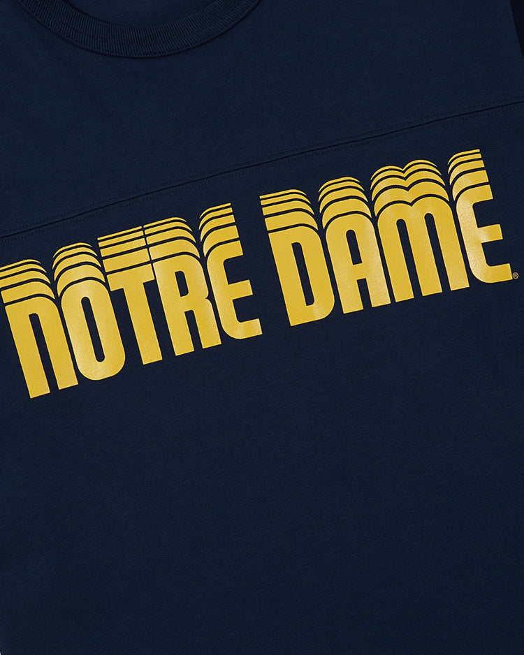 The Ebbets Field NOTRE DAME FOOTBALL TEE NAVY features bold, yellow, retro-style curved NOTRE DAME lettering across the chest.