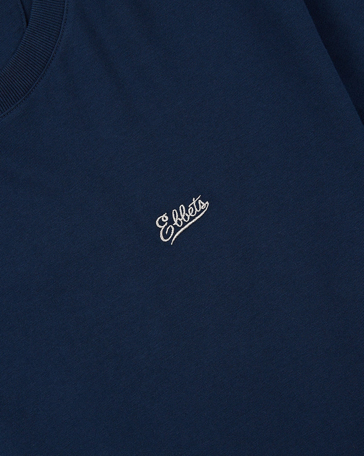 Close-up of the Ebbets Field Brooklyn Bushwicks Ebbets Tee with Back Print in navy, featuring Eldets embroidered in white cursive on the chest.