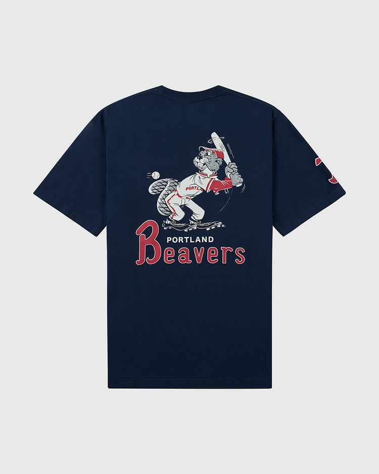The Ebbets Field Portland Beavers Ebbets Tee with Back Print is a navy blue shirt featuring a vintage-style beaver in a baseball uniform with a bat and “PORTLAND Beavers” text below the image.