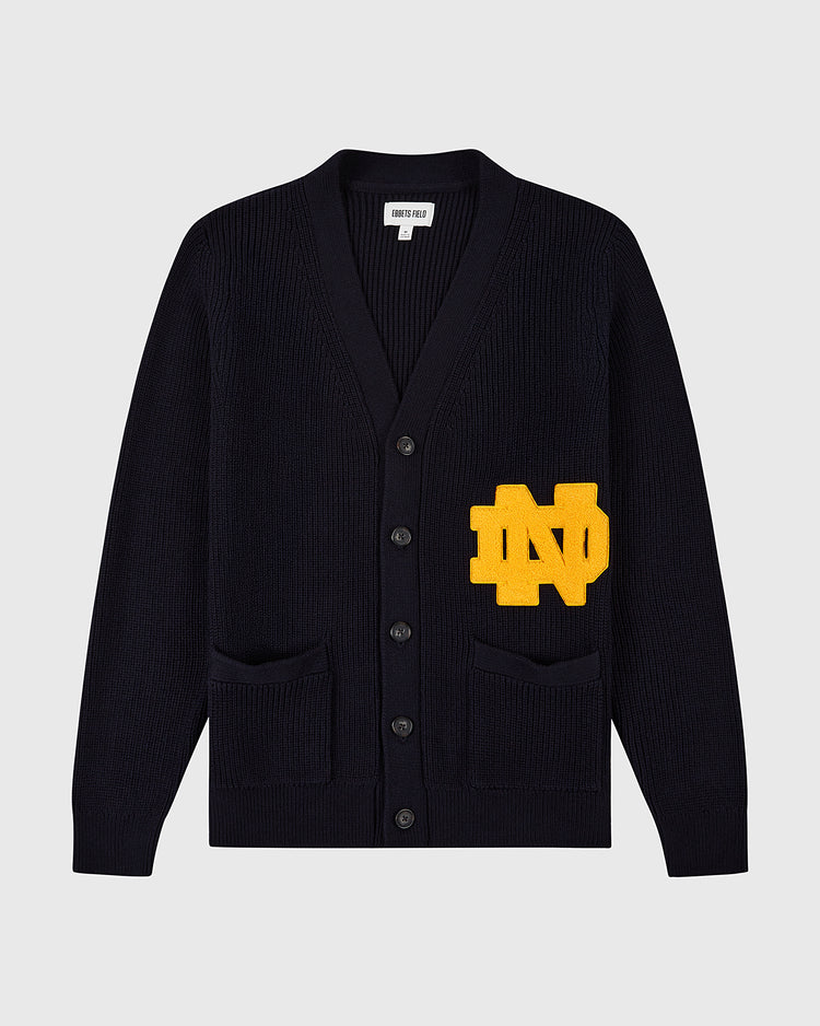 The Ebbets Field NOTRE DAME VARSITY CARDIGAN in navy features two front pockets and a bold yellow ND varsity patch on the left side.