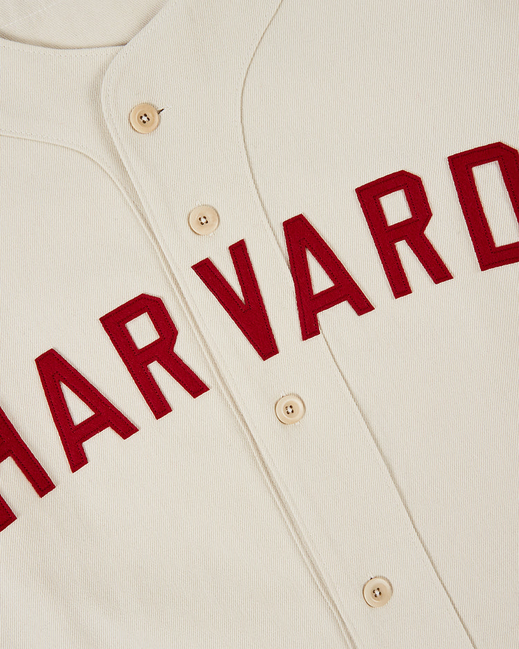 The Ebbets Field HARVARD COTTON TWILL JERSEY Natural is a cream-colored button-up jersey featuring red “HARVARD” lettering across the front.