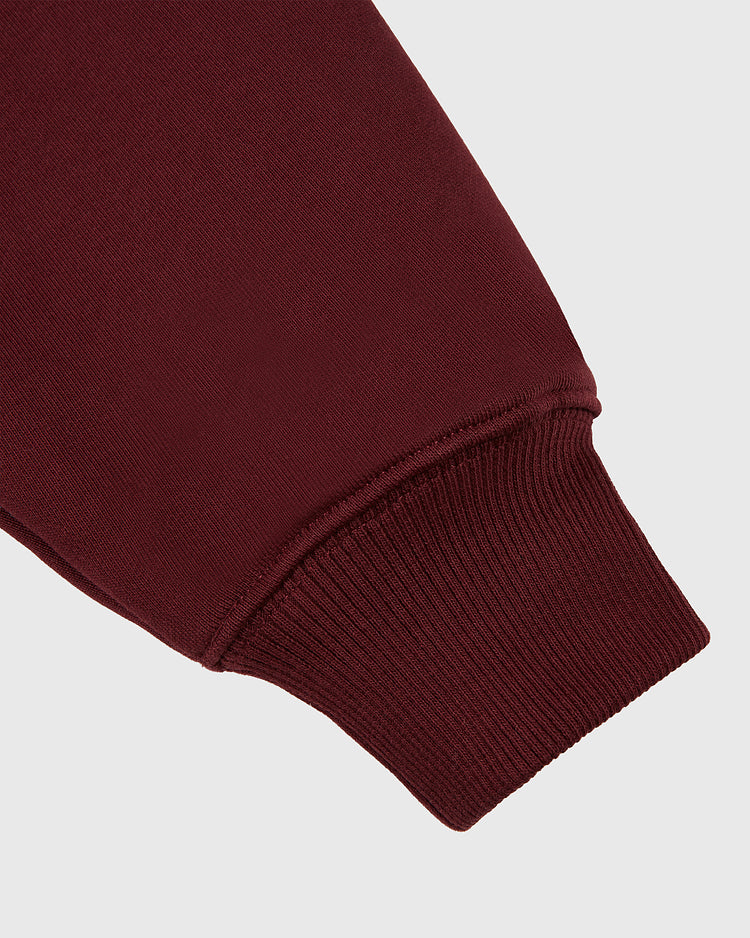 Close-up of the HARVARD HOODIE MAR by Ebbets Field, showcasing its maroon sleeve with a ribbed cuff against a plain light gray background.
