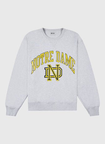 The NOTRE DAME CREWNECK SS H-GRY by Ebbets Field is a light gray crewneck sweatshirt featuring bold yellow NOTRE DAME lettering and a yellow ND monogram at the center.