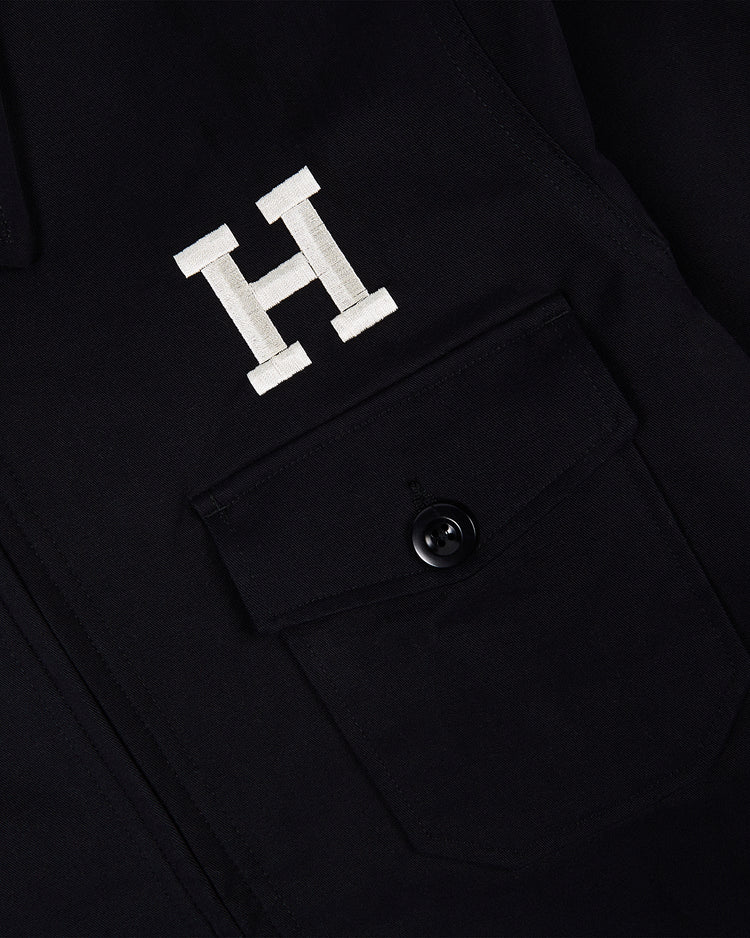 Close-up of the Ebbets Field HARVARD GROUNDS CREW JACKET BLK featuring a buttoned flap pocket and a large white “H” embroidered above it.