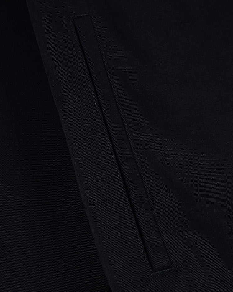 Close-up of the HARVARD GROUNDS CREW JACKET BLK by Ebbets Field, showing a neatly stitched horizontal welt pocket on dark fabric with visible texture and seams.