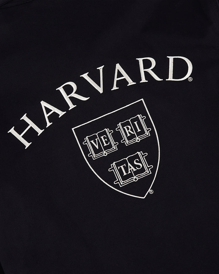 The HARVARD GROUNDS CREW JACKET BLK by Ebbets Field features black fabric with HARVARD in large white letters above a shield displaying VERITAS across three books.