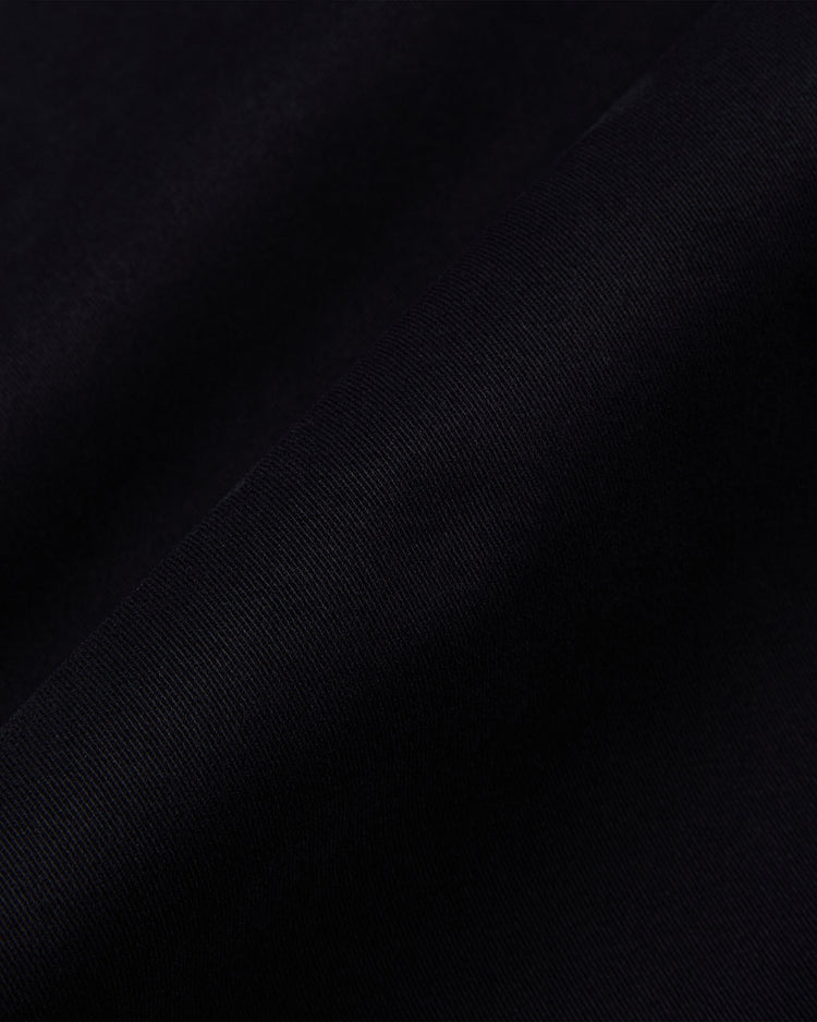Close-up of the HARVARD GROUNDS CREW JACKET BLK by Ebbets Field, showing its soft, black fabric with gentle folds and diagonal shadows.