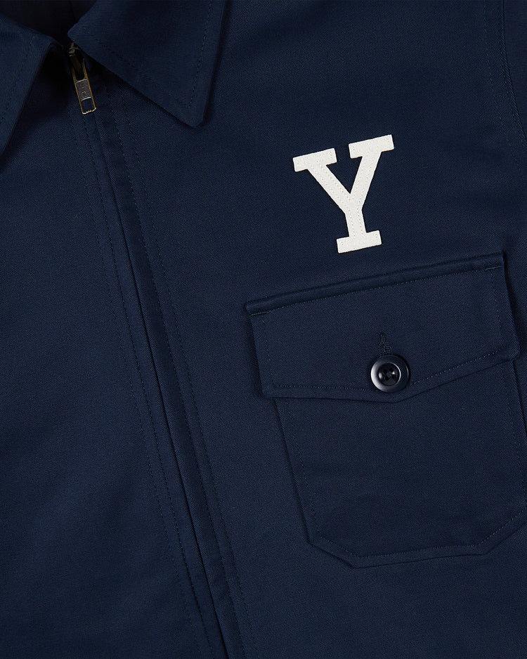 Close-up of the Ebbets Field YALE GROUNDS CREW JACKET in navy, featuring a buttoned chest pocket, a white Y above it, and a partially visible zipper along the front placket.
