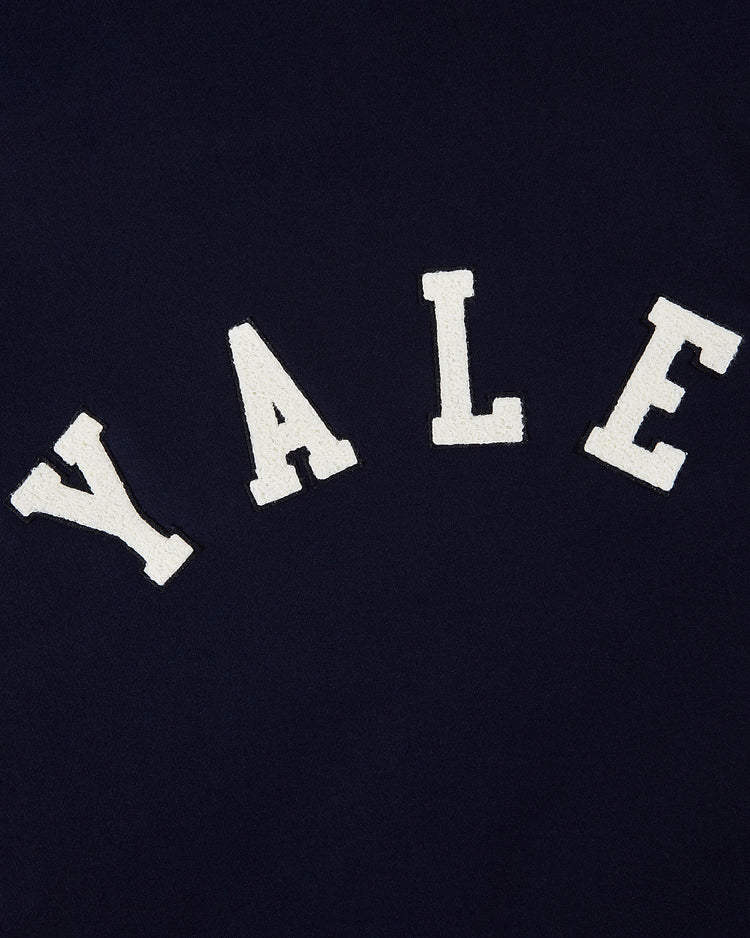 White varsity-style YALE letters are arched across the front of the navy YALE VARSITY JACKET by Ebbets Field.
