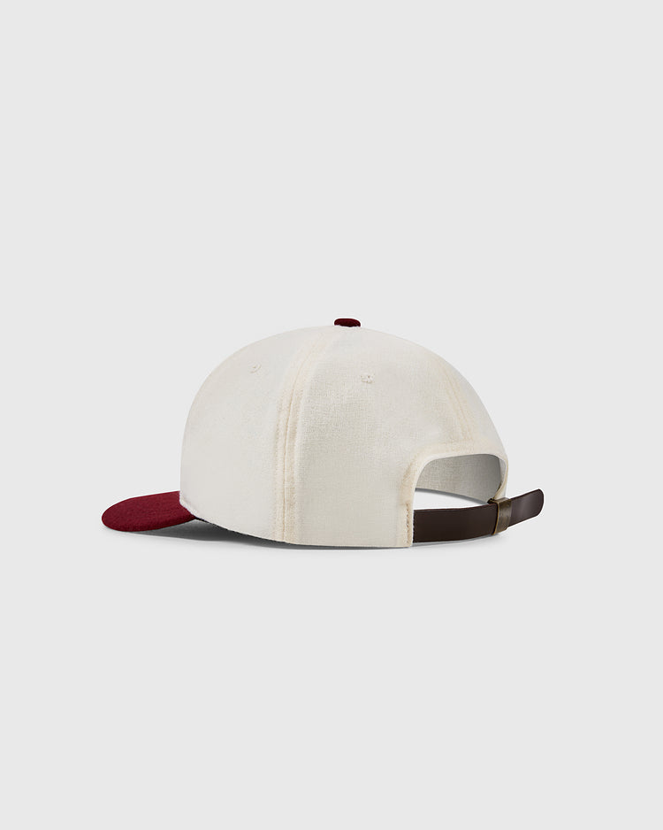 The Texas A&M Aggies Collegiate Wool Ballcap by EFF is shown from the back with a cream crown, burgundy brim, and adjustable brown strap. Inspired by classic college sports mascots, it’s set against a plain light gray background.
