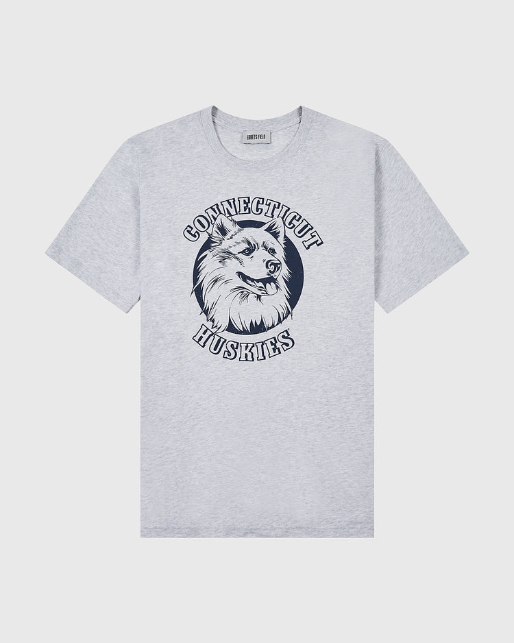 The Ebbets Field UCONN SS TEE H-GRY is a light gray T-shirt with a husky dog head graphic centered, and “Connecticut Huskies” in bold capital letters arching above and below.
