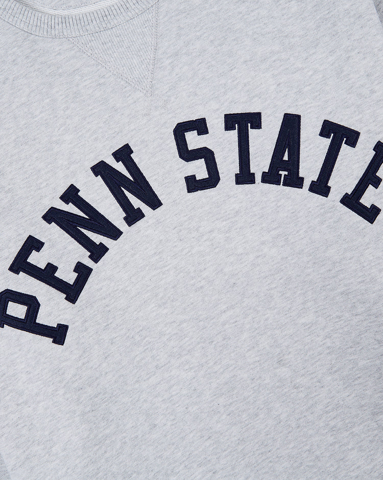The Ebbets Field PENN STATE CREWNECK SS H-GRY is a light gray crewneck featuring bold, black PENN STATE lettering arched across the chest.