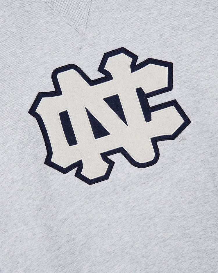 The Ebbets Field UNIVERSITY OF NORTH CAROLINA CREWNECK SS H-GRY is a light gray sweatshirt with a bold, overlapping N and C logo outlined in dark blue on the chest.