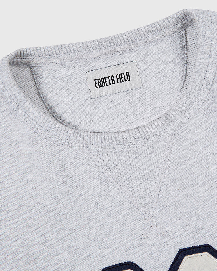 Close-up of the neckline on the UNIVERSITY OF NORTH CAROLINA CREWNECK SS H-GRY sweatshirt by Ebbets Field, featuring ribbed detailing and a label with the brand name.