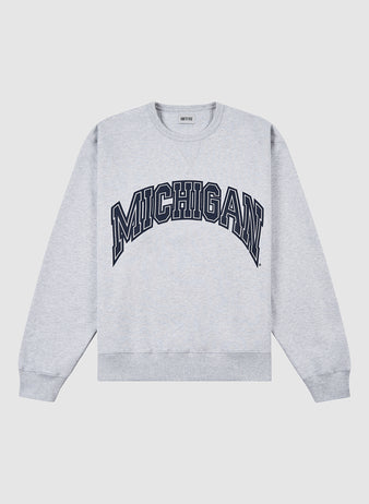 The Ebbets Field MICHIGAN CREWNECK SS H-GRY is a light gray crewneck sweatshirt featuring bold, navy blue MICHIGAN lettering across the chest.