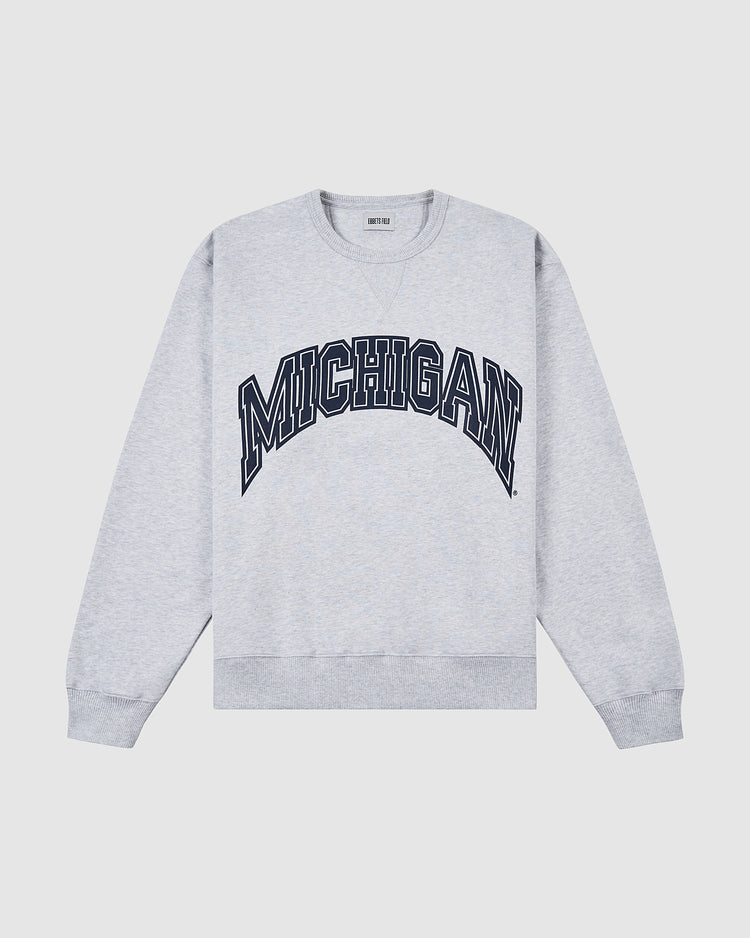 The Ebbets Field MICHIGAN CREWNECK SS H-GRY is a light gray crewneck sweatshirt featuring bold, navy blue MICHIGAN lettering across the chest.