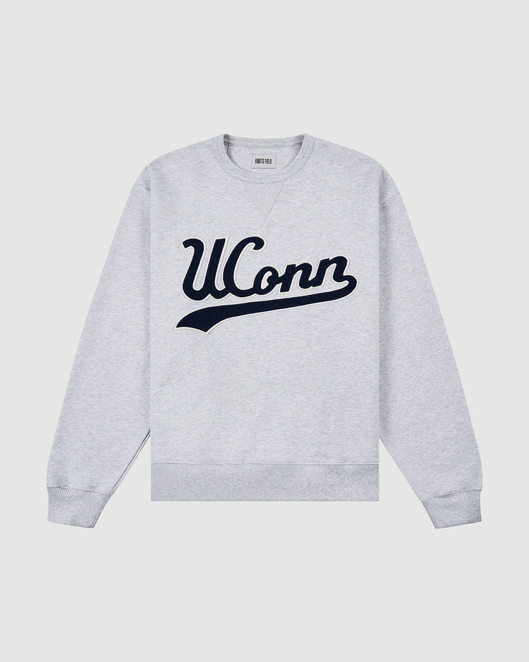 The Ebbets Field UCONN CREWNECK SS H-GRY is a light gray sweatshirt featuring UConn in large navy blue script across the chest, displayed flat on a white background.