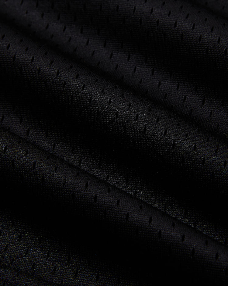 Close-up of Ebbets Field’s Sioux City Ghosts Mesh V-Neck Jersey, showcasing black throwback mesh fabric with small, even perforations and wavy folds—highlighting the unique vintage texture inspired by the legendary fast-pitch softball team.