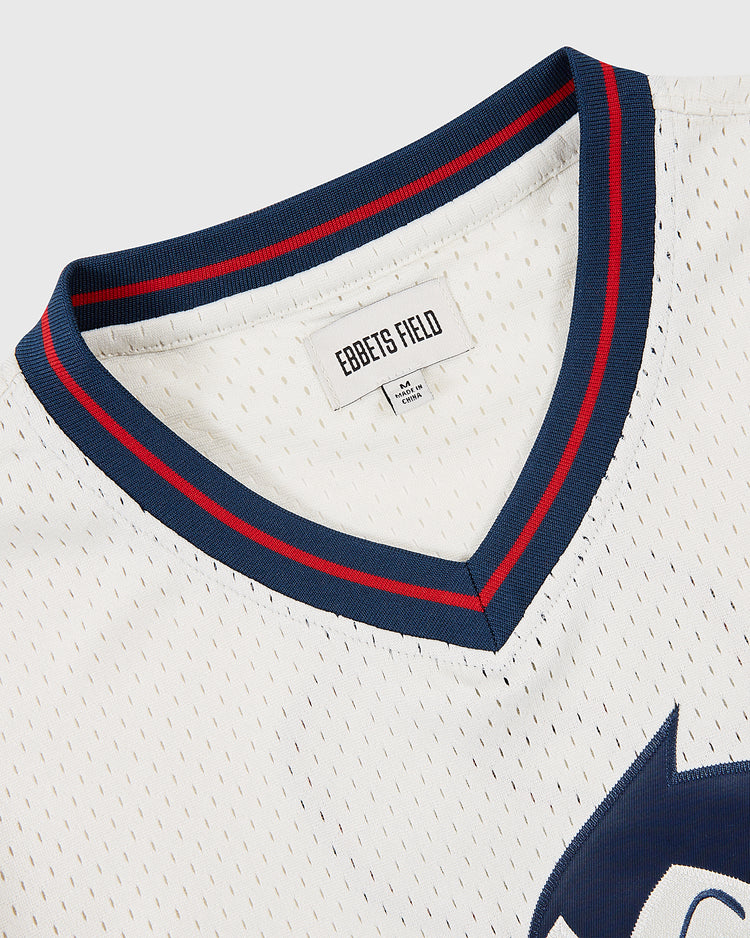 Close-up of the Sankei Atoms Mesh V-Neck Jersey by Ebbets Field, featuring a white mesh collar with navy and red trim, EBBETS FIELD tag, and a partial blue Astro Boy graphic honoring the iconic Atoms baseball team.
