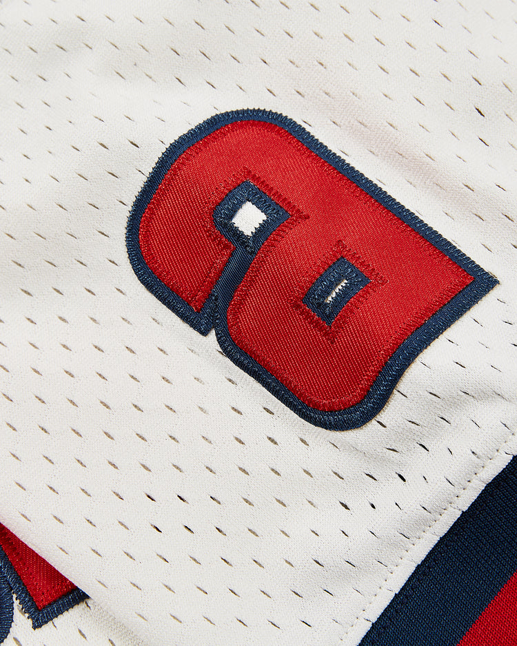 Close-up of the Sankei Atoms Mesh V-Neck Jersey by Ebbets Field, featuring white perforated fabric with a bold red and blue stitched number 90, inspired by the classic Atoms Boy baseball team style.