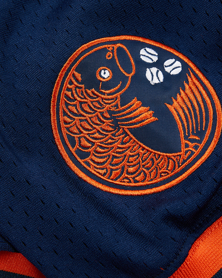 The Ebbets Field Hiroshima Carp Mesh V-Neck Jersey features navy blue fabric with an orange koi fish in a circle and three white baseballs above its tail, honoring Japanese baseball and historic Carp team logos.