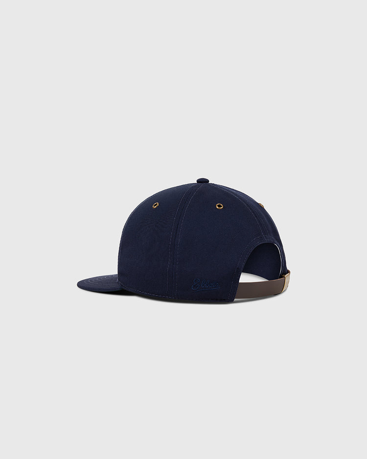 The Ebbets Field Sankei Atoms Cotton Twill Ballcap features navy blue fabric, gold eyelets, a curved brim, and an adjustable brown strap, inspired by Japanese baseball history, shown on a plain white background.