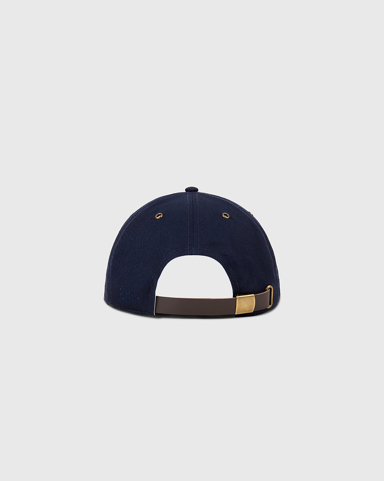The Sanke Atoms Cotton Twill Ballcap by Ebbets Field is shown from the back in navy blue, featuring a brown adjustable strap with gold buckle and two metal ventilation eyelets against a plain light gray background.
