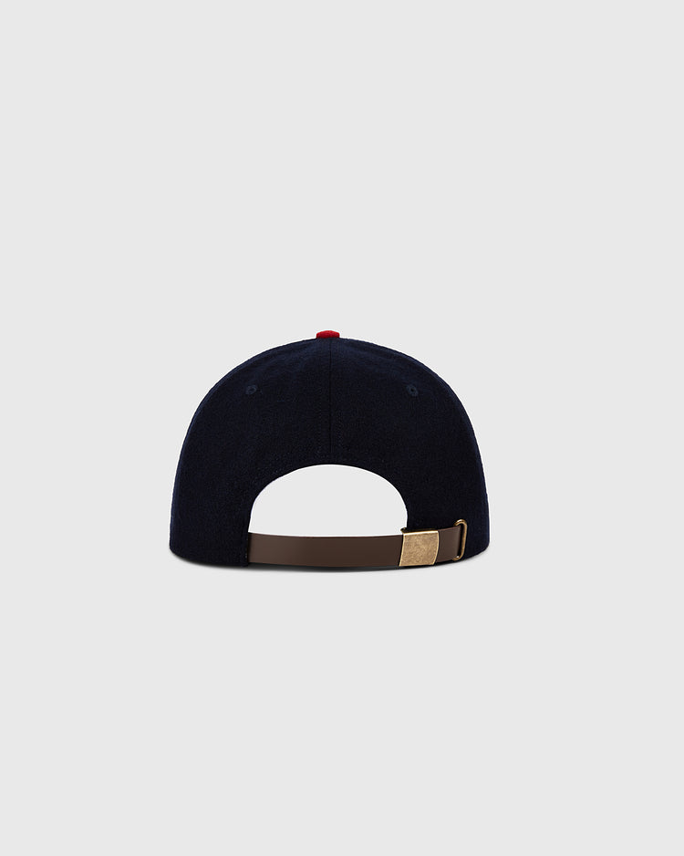 The Minnesota Twin 1961 MLB Authentic Wool Ballcap by Ebbets Field is shown from the back, highlighting its dark blue color, brown adjustable strap with gold buckle, all set against a plain light gray background.