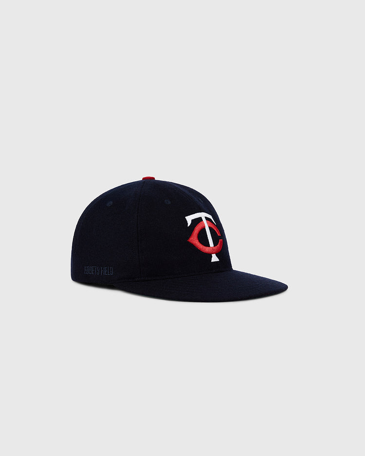 The Ebbets Field Minnesota Twins 1961 MLB Authentic Wool Ballcap features a navy blue design with a red and white TC logo, Target Field embroidery, and is inspired by the original 1961 cap, shown on a plain light grey background.