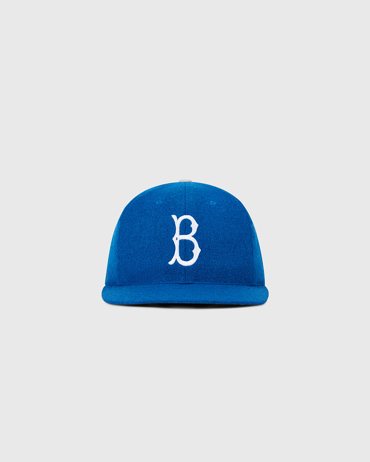 The Ebbets Field Brooklyn Dodgers 1955 MLB Authentic Wool Ballcap is blue with a white embroidered B on the front, inspired by the original on-field design, shown on a plain light gray background.
