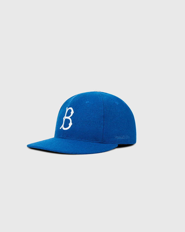 A Brooklyn Dodgers 1955 MLB Authentic Wool Ballcap by Ebbets Field, royal blue with a white cursive “B” on the front, is displayed against a plain light gray background.