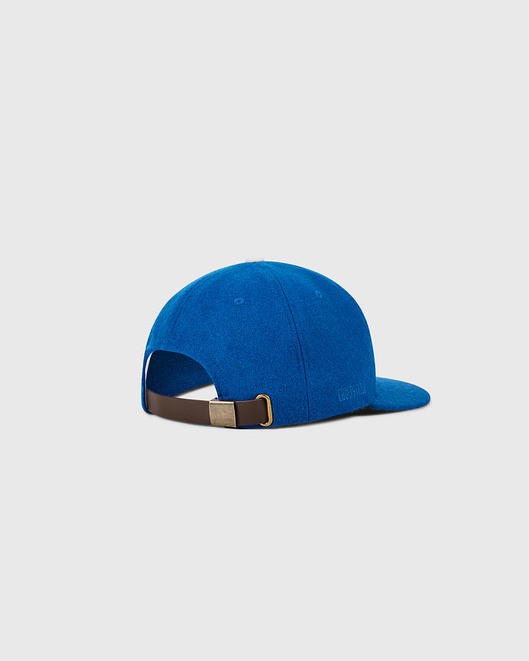 A Brooklyn Dodgers 1955 MLB Authentic Wool Ballcap by Ebbets Field is shown from the back and side, featuring a blue design with a brown adjustable strap and gold buckle, set against a plain light gray background.