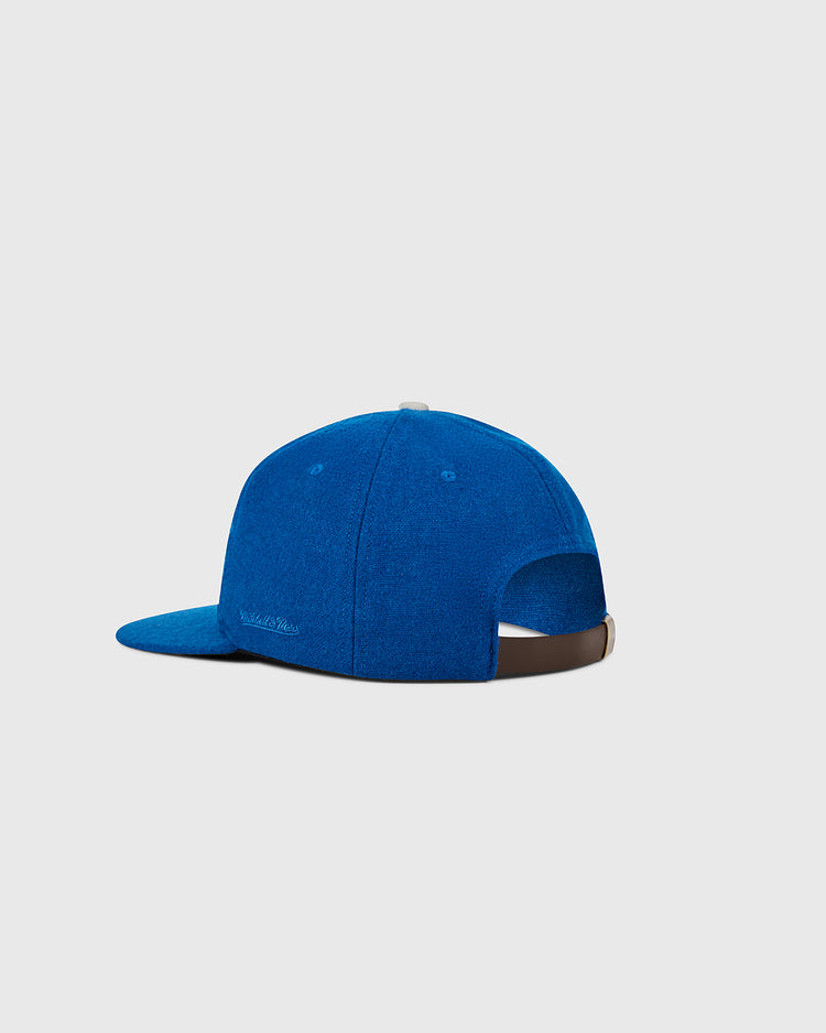 The Ebbets Field Los Angeles Dodgers 1958 MLB Authentic Wool Ballcap, from the Decade of Change Collection, is shown from the back in royal blue with a brown adjustable strap and subtle side logo. Plain light gray background.