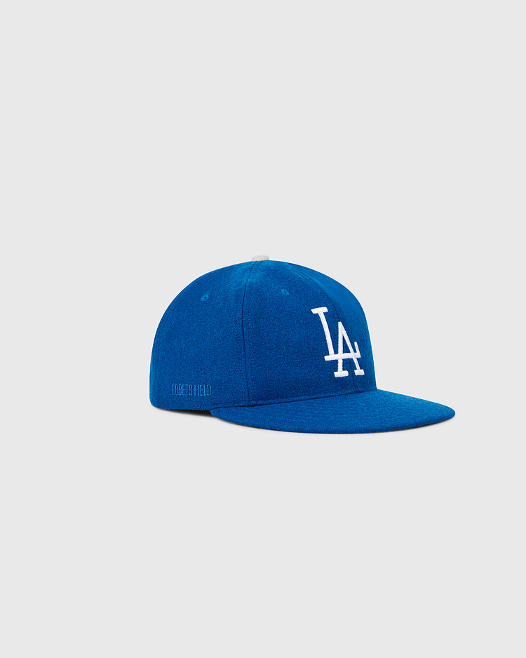 The Ebbets Field Los Angeles Dodgers 1958 MLB Authentic Wool Ballcap features white LA lettering on royal blue wool with a flat brim, shown on a light gray background. It’s part of the Decade of Change Collection.