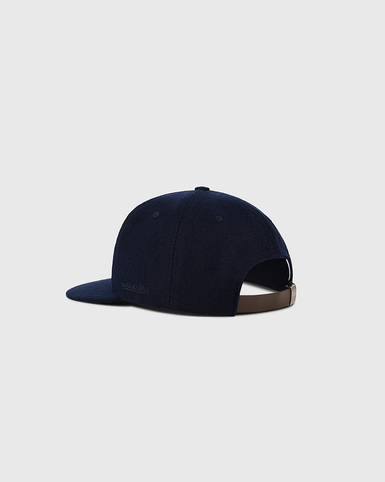 A navy Detroit Tigers 1958 MLB Authentic Wool Ballcap by Ebbets Field, shown from the back with a curved brim and adjustable brown strap with metal clasp. Part of the Decade of Change Collection. Plain light gray background.