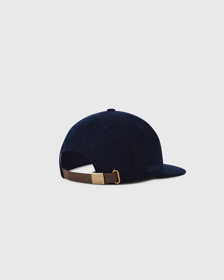 A navy blue Ebbets Field Boston Red Sox 1955 MLB Authentic Wool Ballcap is shown from the back and side, featuring a brown adjustable strap with gold buckle, inspired by on-field caps and set against a light gray background.